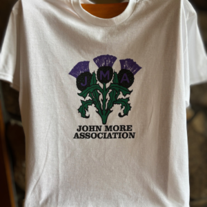 Image of white t-shirt with a three thistle logo with the words "John Mora Association" underneath.